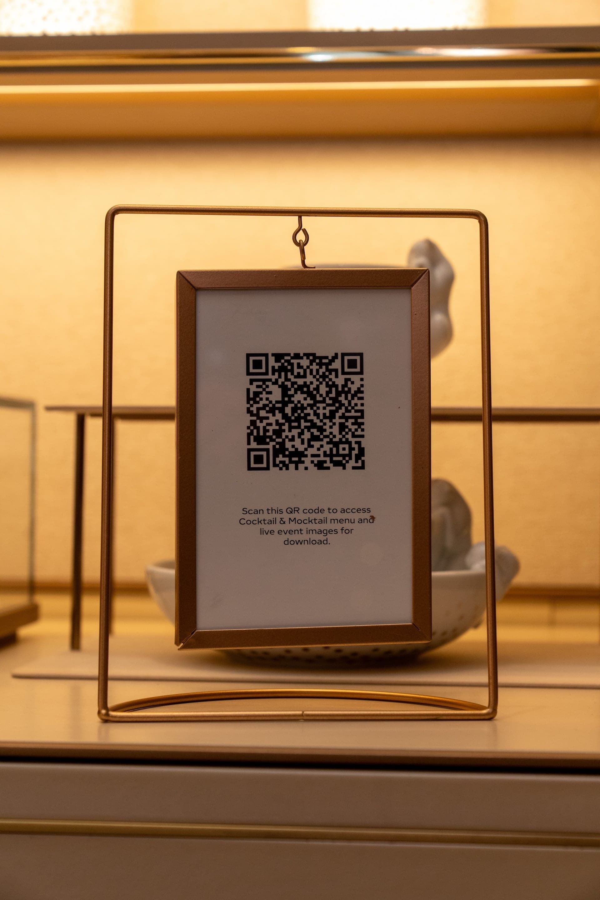 A framed QR code on an event table, inviting guests to scan for their photos